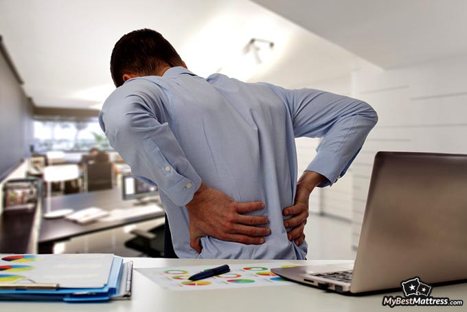 Best mattress topper for back pain: a man holding his back in pain.