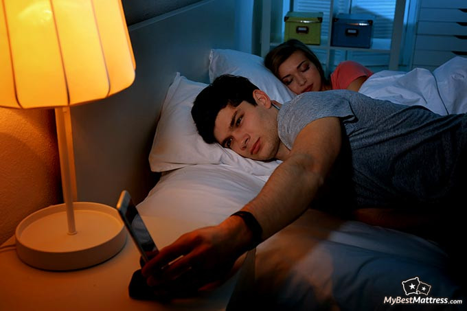 Best sleep tracker: a man going to sleep and turning on his tracker.