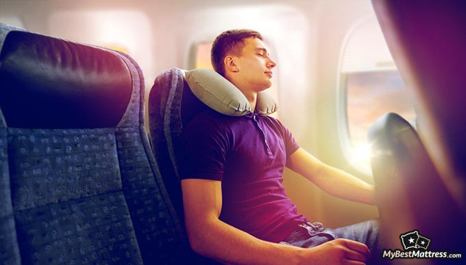 Best travel pillow: a man sleeping in an airplane with a travel pillow.