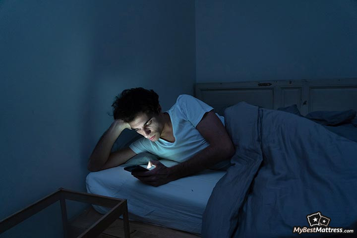 Coronavirus insomnia: a man browsing social media in bed.