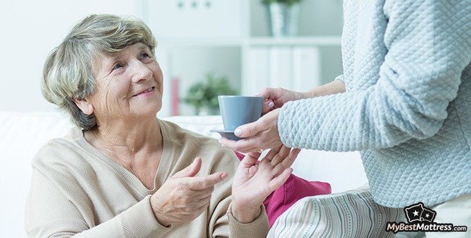 Green Tea Before Bed: Elderly woman being given a cup of green tea.