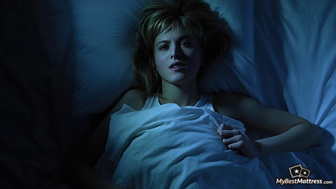 How to cure insomnia: a woman lying in bed, with a horror-stricken facial expression. How to cure insomnia: a woman lying in bed, with a horror-stricken facial expression.