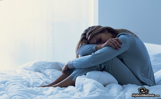 How to cure insomnia: a woman dozing off, while sitting on the bed. How to cure insomnia: a woman dozing off, while sitting on the bed.