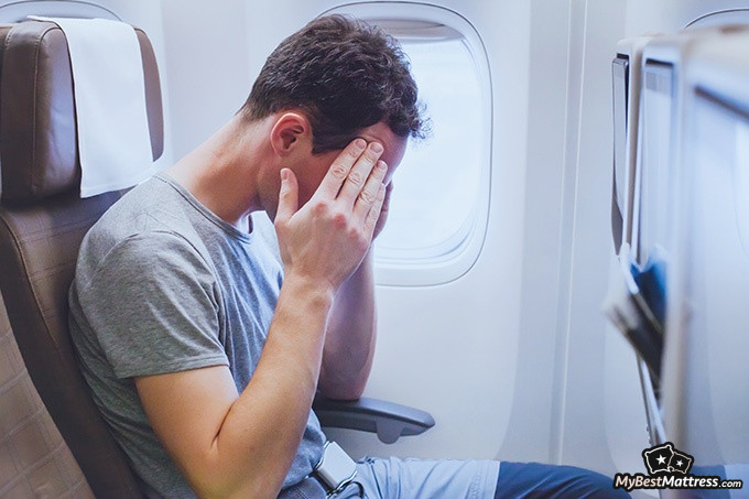 How To Sleep On A Plane: a man suffering from jet lag.
