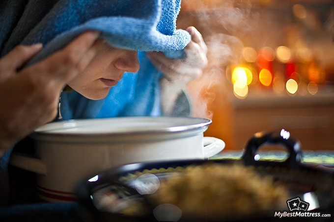 How To Sleep With A Cold: woman inhaling steam to help with congestion.