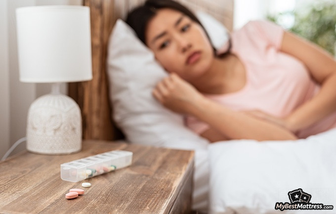 How to Stop Drooling: a woman in bed looking at her medication.