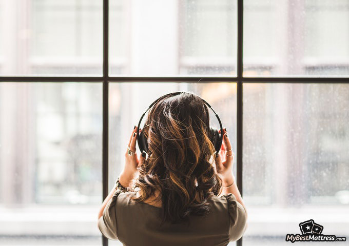 Hypnosis For Sleep: woman with headphones looking through the window.