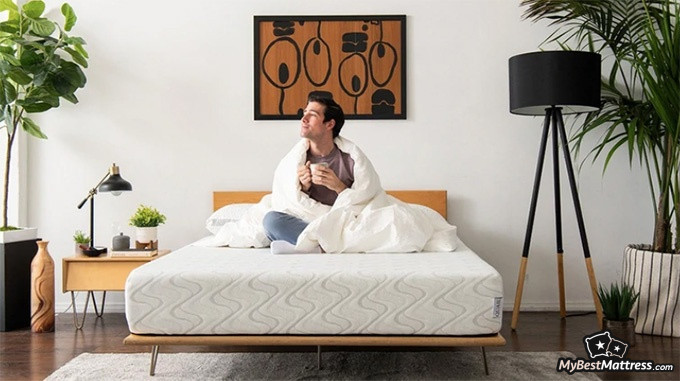 Love & Sleep mattress review: a man is comfortably sitting on the Nest Love and Sleep mattress with a mug and a blanket Love & Sleep mattress review: a man is comfortably sitting on the Nest Love and Sleep mattress with a mug and a blanket