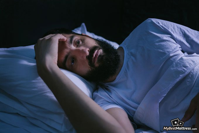 Natural sleep aid: man overthinking while lying in bed Natural sleep aid: man overthinking while lying in bed