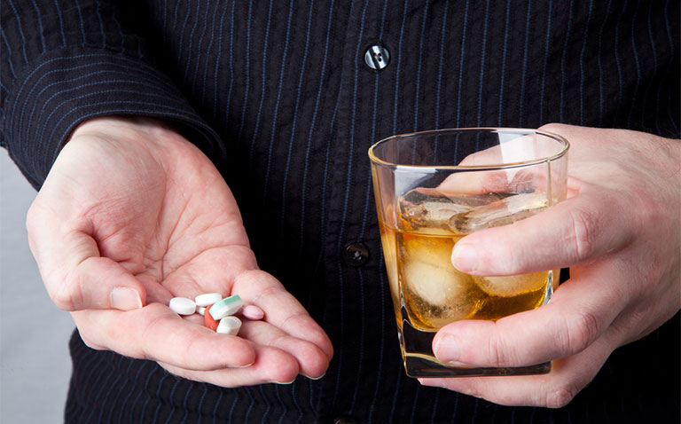 Melatonin an Alcohol: man holding a glass of alcohol and pills Melatonin an Alcohol: man holding a glass of alcohol and pills