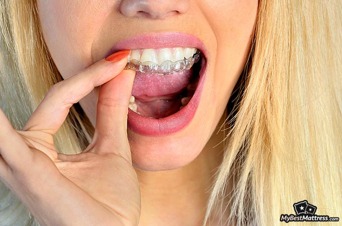 Mouth guard for teeth grinding: a woman inserting a mouth guard into her mouth.