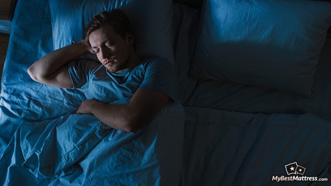 Sleep Learning: man sleeping in his bed in dim lighting.