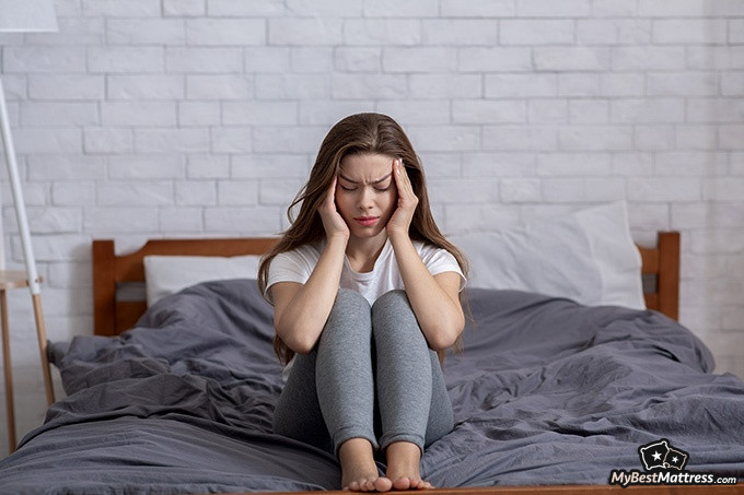 What is Parasomnia; a woman is massaging her temples What is Parasomnia; a woman is massaging her temples