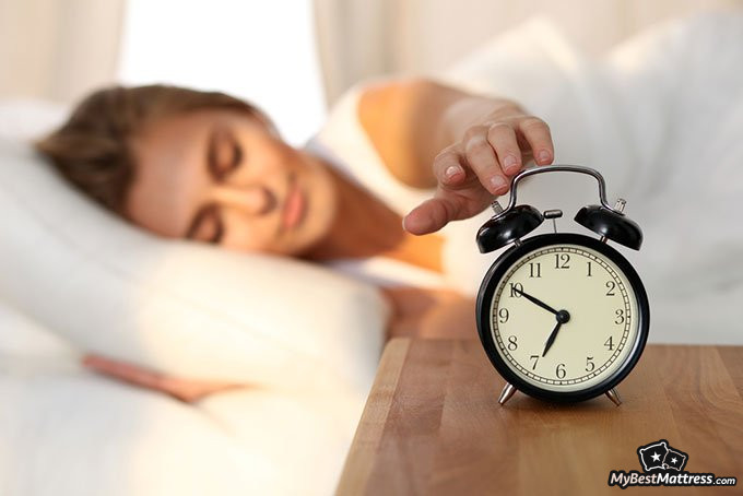 Natural sleep aid: woman pressing alarm clock Natural sleep aid: woman pressing alarm clock