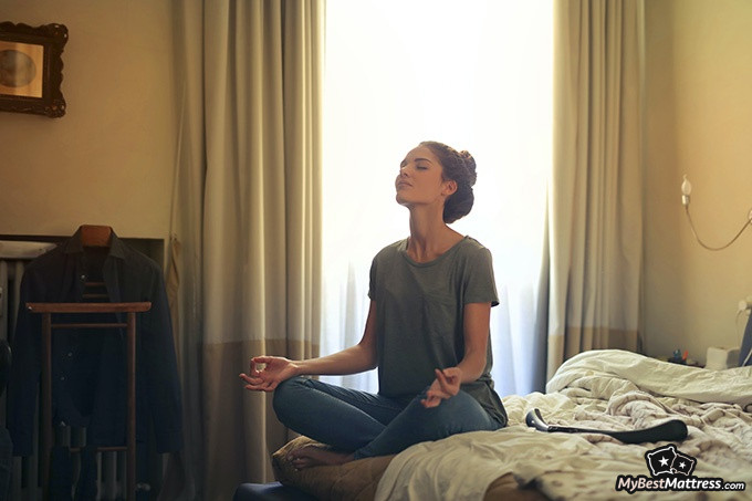 Yoga before bed: a woman meditating on her bed.